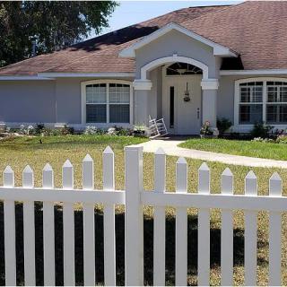 A suburban home with a white picket fence and a well-maintained lawn.