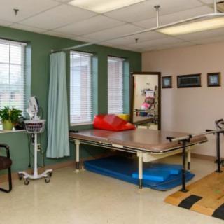 A physical therapy room equipped with a treatment table and various exercise equipment.
