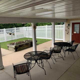 A covered outdoor patio with tables and chairs next to a fenced area.