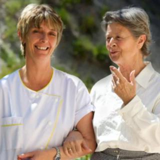 A caregiver and an elderly woman enjoying a conversation outdoors.