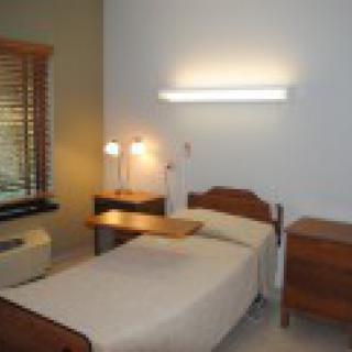 A minimalist single bedroom with basic furniture and a window.