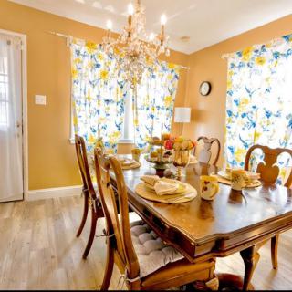 A warm and inviting dining room with a wooden table set for a meal, adorned with a chandelier overhead.