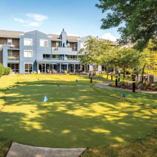 A sunny view of a building with a well-maintained lawn and trees.