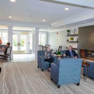 A modern and comfortable living room with people seated, featuring stylish furniture and decor.