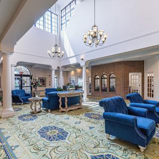 A luxurious and spacious lobby with elegant blue furniture and chandeliers.