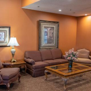 A cozy living room with orange walls, featuring a sofa set, a glass coffee table, and decorative artwork.