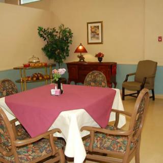 A cozy dining area featuring a table with a red tablecloth, surrounded by wooden chairs, and complemented by warm decor.