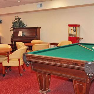 A cozy recreation room featuring a pool table, piano, and seating area with a popcorn machine.