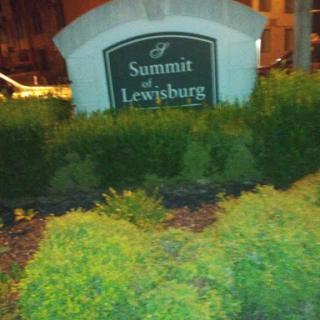 A nighttime view of the Summit at Lewisburg sign surrounded by greenery.