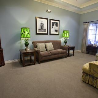 A cozy living room featuring a sofa, vibrant green lamps, and framed artwork.