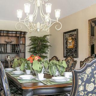 An elegant dining room with a beautifully set table, featuring plants and a chandelier.