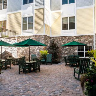 An outdoor patio with tables, chairs, and umbrellas next to a building.