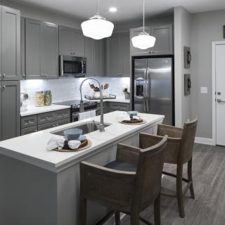 A modern kitchen with a central island, bar stools, and sleek appliances.