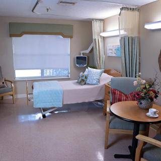 A hospital room featuring a bed, medical equipment, and seating area.