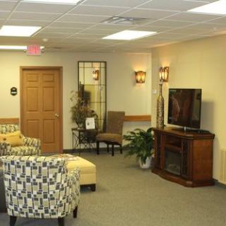 A cozy waiting room with comfortable seating, a television, and indoor plants.