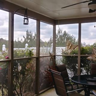 A cozy screened-in porch with patio furniture and plants, offering a view of the outdoors.