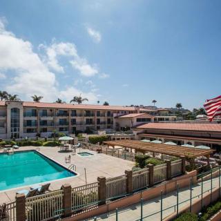 A hotel with a swimming pool under a clear blue sky.
