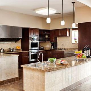 A modern kitchen with a large island and granite countertops, featuring stainless steel appliances and pendant lighting.