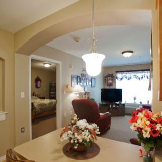 A cozy living room with comfortable seating, a television, and decorative flowers.