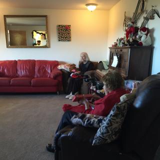 A cozy living room with people sitting on sofas, surrounded by decor and a large mirror.