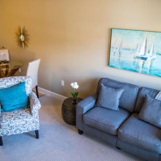A cozy and well-decorated living room with a comfortable sofa, stylish armchair, and vibrant artwork.