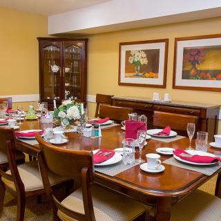 A warmly lit dining room with a table set for a meal, featuring plates, glasses, and cutlery.