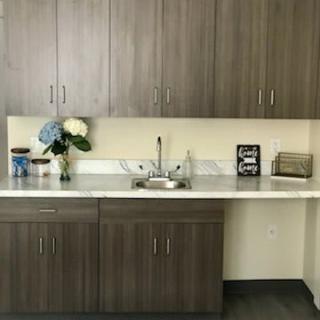 A modern kitchen area with wooden cabinets, a countertop, and decorative flowers beside the sink.