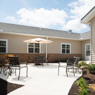 A sunny outdoor patio area with a table, chairs, and a sun umbrella.