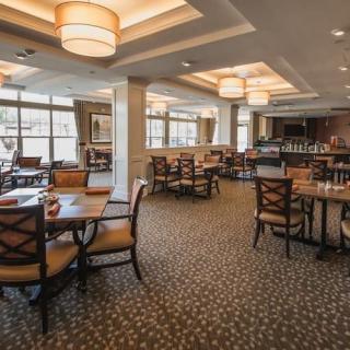 An elegantly designed restaurant dining area with neatly arranged tables and chairs, featuring large windows and stylish lighting.