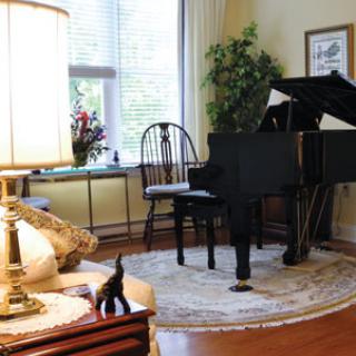 A cozy living room with a grand piano, an elegant chair, and decorative elements.