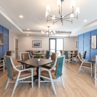A modern dining area with stylish chairs and tables, featuring blue accents and a chandelier.