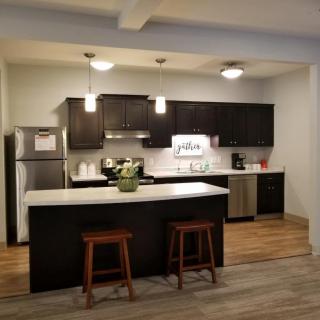 A modern kitchen with dark cabinets, a central island, and stylish bar stools.