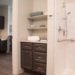 A stylish and modern bathroom featuring sleek cabinets, open shelves, and a clean shower area.