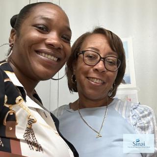 Two people smiling for a selfie indoors.