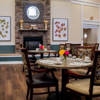 A cozy dining area with a beautifully set table and a fireplace surrounded by artwork.