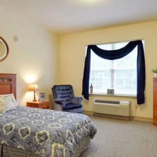 A cozy bedroom with a bed, chair, and window adorned with curtains.
