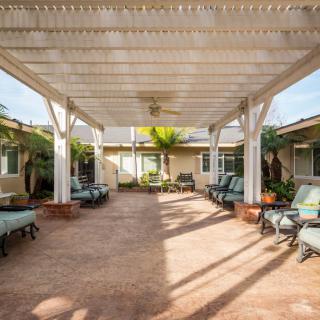 A spacious courtyard with a pergola, featuring outdoor seating and tropical plants.