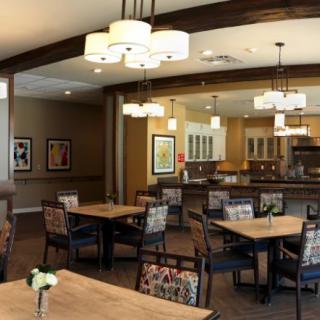 A modern dining area with wooden tables and cozy seating, featuring elegant lighting fixtures.