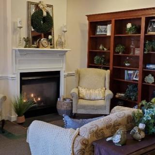 A cozy living room with a fireplace, armchair, and bookshelf, highlighting warm home decor.