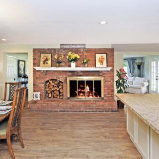 A cozy living room with a brick fireplace, open layout, and dining area.