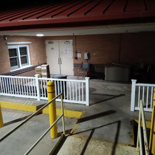 A view of a building's exterior at night, featuring stairs and a door.