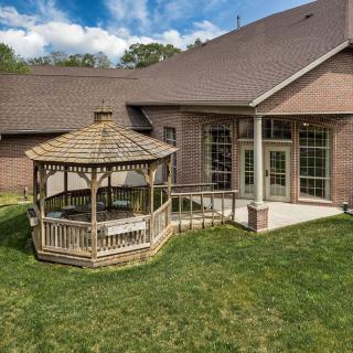 A backyard featuring a wooden gazebo and patio attached to a brick house.