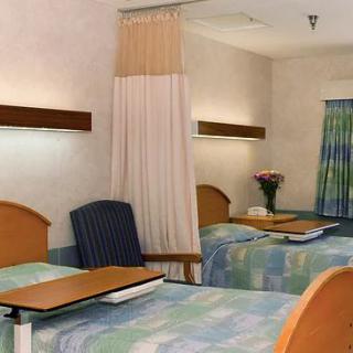 A hospital room with two beds and a privacy curtain.