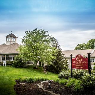 A serene countryside building with a prominent sign and lush greenery.
