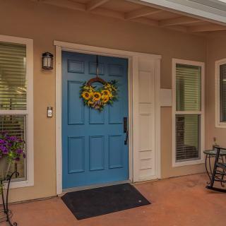 A welcoming blue front door adorned with a floral wreath, situated on a cozy porch.