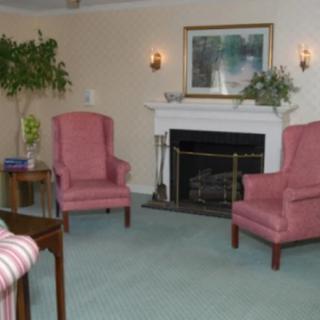 A cozy living room with two pink armchairs, a fireplace, and wall art.