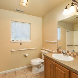 A clean and well-lit bathroom with a sink, toilet, and mirror.