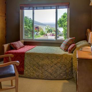 A cozy bedroom with a large window offering a scenic view of the outdoors, complete with comfortable furnishings and warm decor.