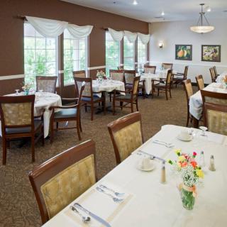 An elegantly set dining room with multiple tables and chairs, large windows, and tasteful decor.