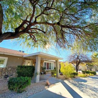 A sunny suburban house with a large tree casting shadows in the yard.
